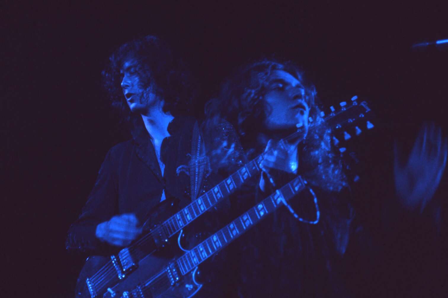 Jimmy Page steht im Schwarzlicht mit Doppelhals Gitarre auf der Bühne